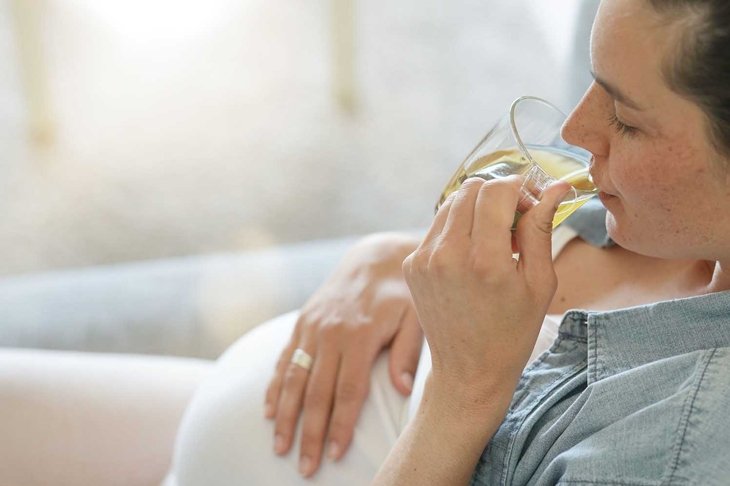Pregnant woman relaxing in sofa drinking hot tea