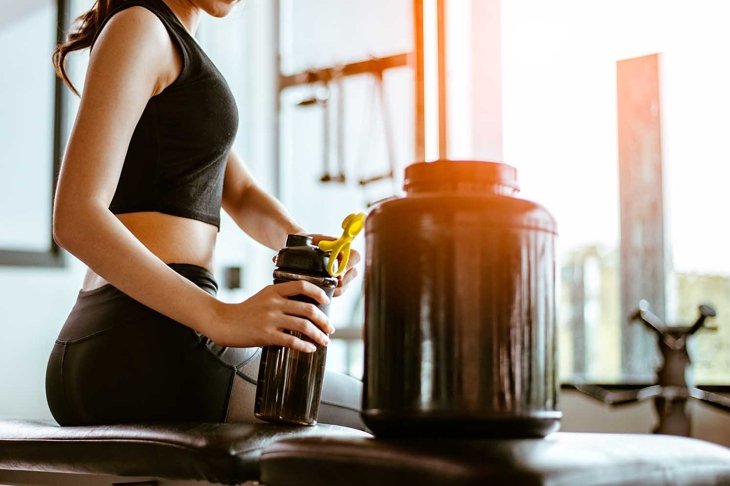 Relaxing after training.beautiful young woman looking away while sitting at gym.young female at gym taking a break from workout.woman brewing protein shake.